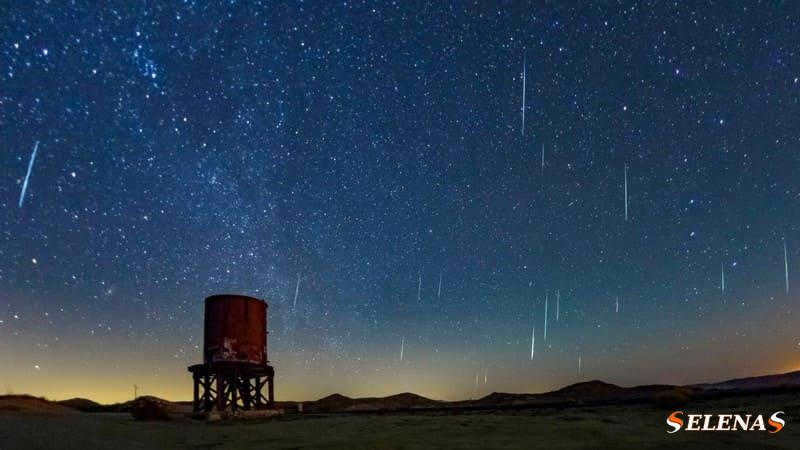 Meteors streak across the starry sky over a large cistern in the desert.