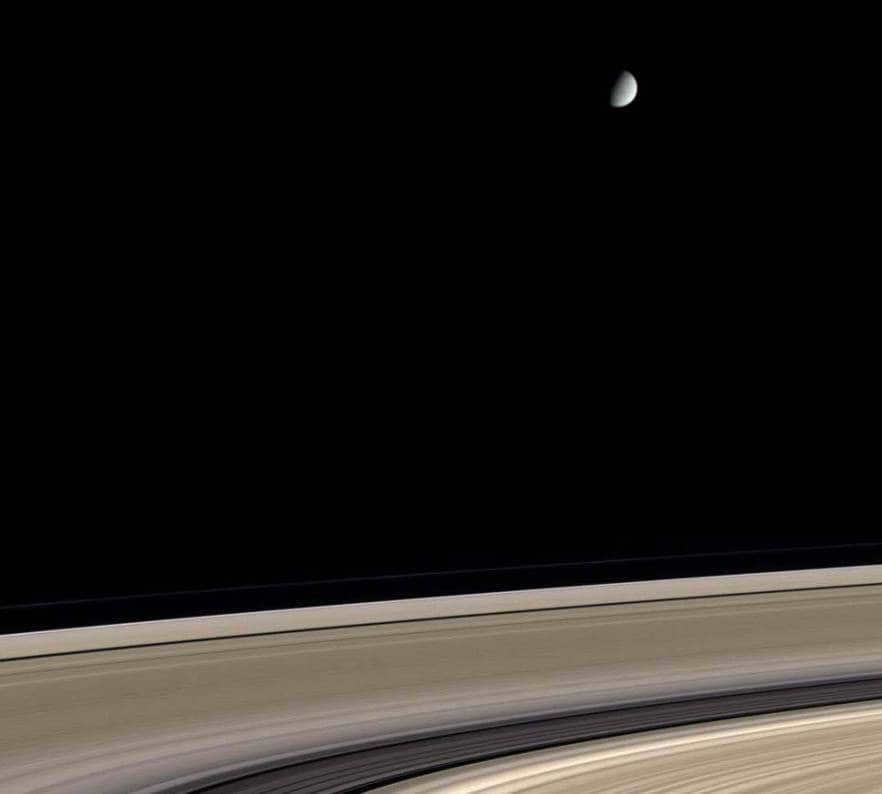 Saturn's icy satellite Enceladus orbits above the planet's magnificent ring system in Cassini's color view. The rings are represented by almost pure water ice, some of which is contaminated with meteorite dust. It may be several hundred million years old. Enceladus is also composed almost entirely of water ice, but has escaped contamination for reasons as yet unclear. It covers a width of 505 kilometers. 