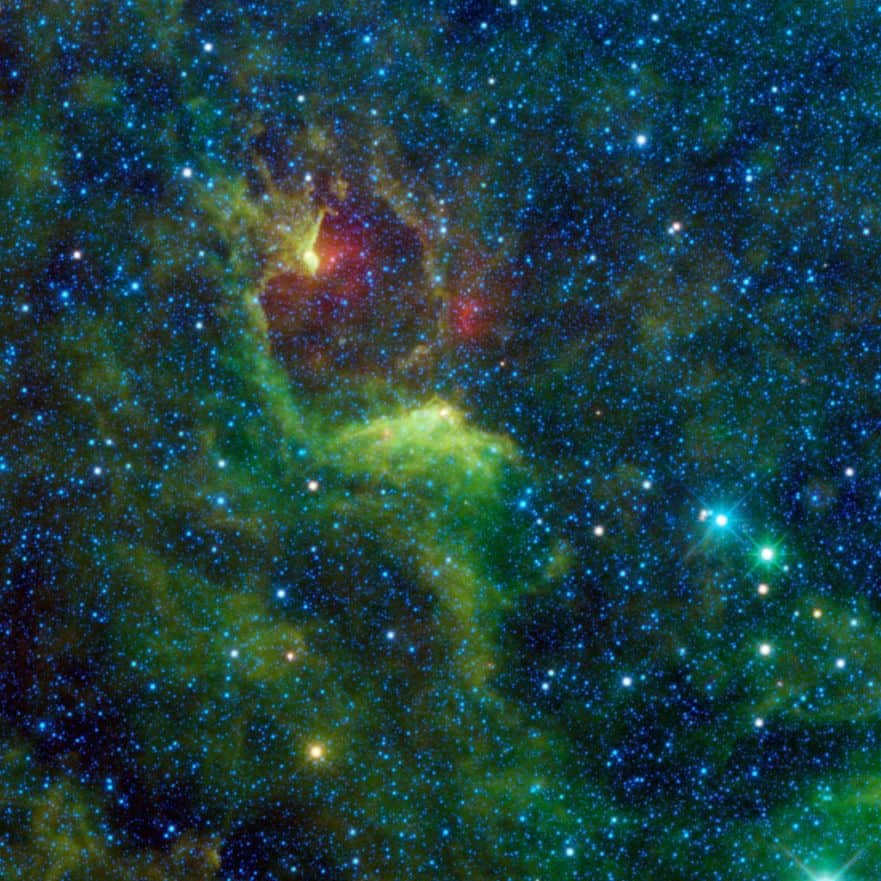 Epsilon of the Southern Cross (bright blue star at right) and the reflective nebula IRAS 12116-6001 (green). The cloud of interstellar dust cannot be seen in visible light, but WISE detectors have captured it in infrared wavelengths. IRAS 12116-6001 is a carbon star nearing the end of its life cycle. Blue is emission at 3.4 and 4.6 microns, and green at 12 microns.
