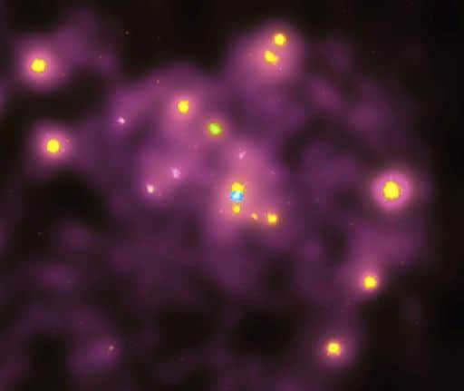 An X-ray source is visible at the galactic center of M31, corresponding to a black hole millions of times the solar mass. The false-light image shows X-ray emission from a probable double star in the central region (yellow dots). The blue source correlates with the location of the black hole. The X-rays are produced when the material hits the black hole, but the analysis shows that the center point is cool.