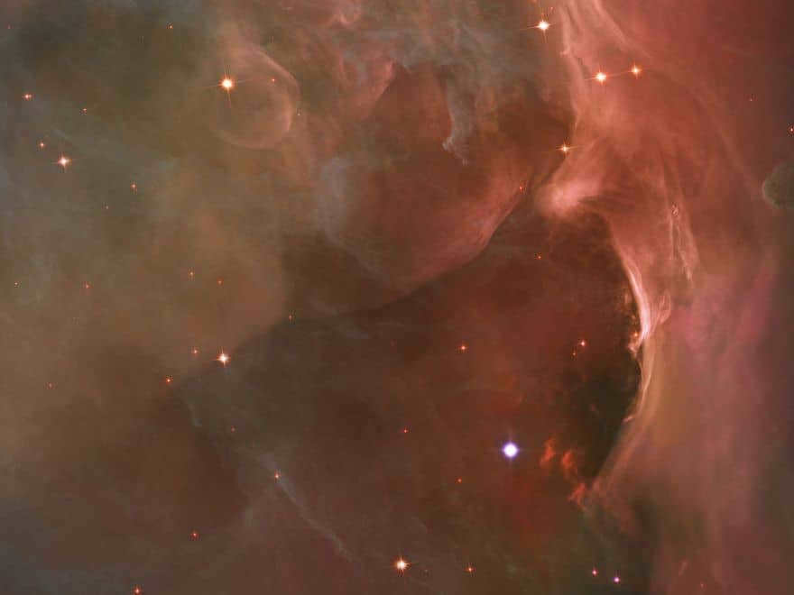 The luminous region shows bubbles and arcs formed when stellar winds (streams of charged particles) collide with material.