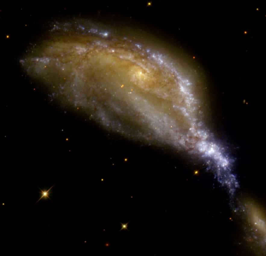 NGC 6745 is a large spiral galaxy with a nucleus. It is located opposite the smaller one (in the lower right corner, it is almost invisible). Their path is shown by bright blue and yellow-white stars that together resemble a bird's face and beak. The galaxies did not just interact, but passed through each other. When galaxies collide, stars usually do not collide and pass freely with little damage. But interstellar clouds suffer in the process. Because of the high velocities, pressure is created. The blue stars in the image prove the presence of star formation.