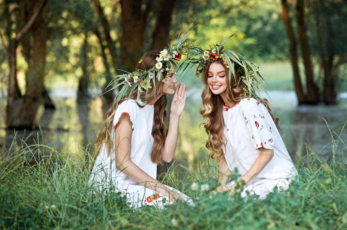 Girls in wreaths sitting on the grass.