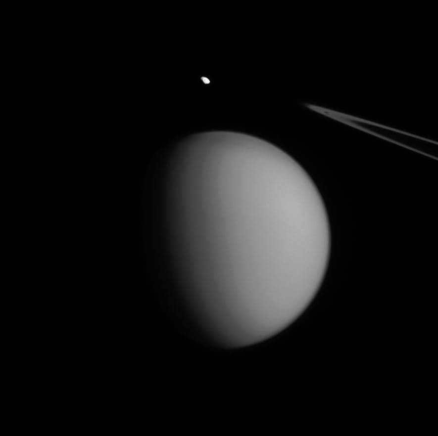 Cassini has managed to position itself so that Pandora stands over Titan, and the image resembles an accent mark. Tiny Pandora (81 km) is closer to the instrument than Titan (5150 km and three times farther away). The image was taken on July 4, 2015. The northern part of Titan is rising and rotating 19 degrees to the right. The instrument was positioned at a distance of 1.9 million kilometers from Titan at a scale of 12 kilometers per pixel and 698,000 kilometers from Pandora at a scale of 4 kilometers per pixel. A narrow-angle camera with green light was used for the survey. The Cassini program acts as a joint development of ESA, NASA and the Italian Space Agency. The team is housed at LRD. The two cameras on board are also built by them. The extracted photos are being processed in Boulder, Colorado.