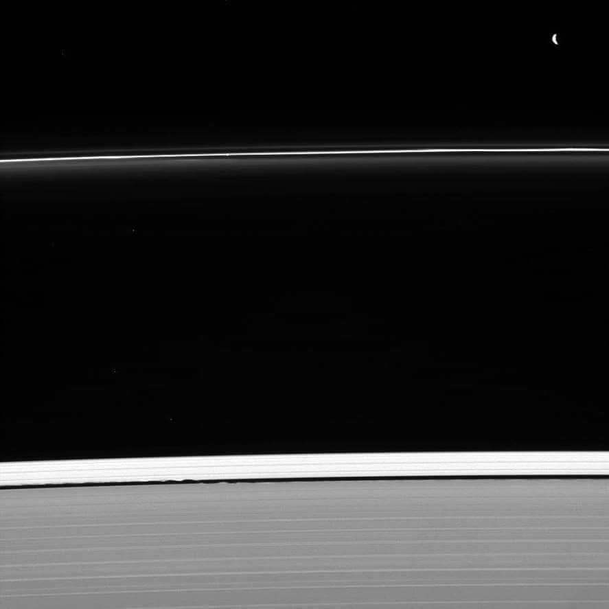 On January 30, 2013, Cassini managed to capture two of Saturn's ring-forming satellites. Pandora (top right) is refilling the F ring along with Prometheus (not included in the frame). Daphnis (bottom center) is busy enlarging the Keeler slit. The faint companion appears at the point where the outer and inner waves converge. It was also possible to capture the star shining above the ring. Observations show that satellites make contact with the rings, moving particles away from themselves. The dusty elements feel small gravitational jolts and collide with other elements, losing orbital momentum. This is how the Keeler gap came to be. A narrow-angle camera with visible light was used for the survey. They observed the unlit side of the rings 50 degrees below the ring plane. The Cassini program acts as a joint development of ESA, NASA and the Italian Space Agency. The team is housed in the LRD. The two cameras on board are also built by them. The extracted photos are being processed in Boulder, Colorado.