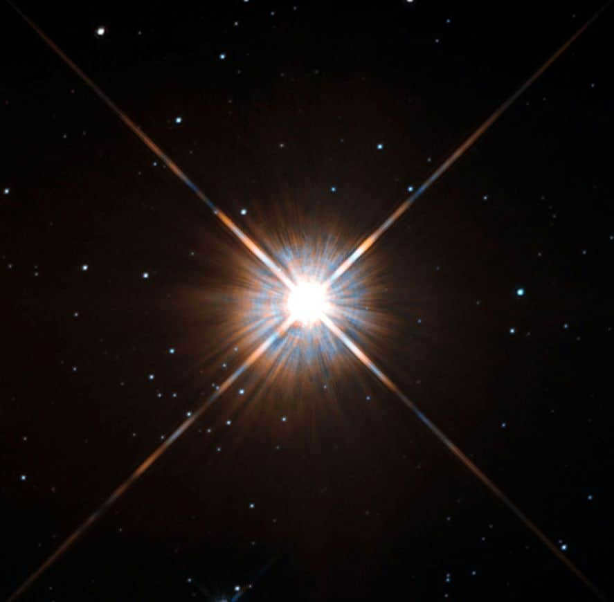 The Hubble telescope was able to capture the bright glow of the nearest star, Proxima Centauri. It resides in the constellation Centauri at a distance of 4 light years. It appears bright here, but it cannot be found with the naked eye. The average visibility is extremely low, and the mass reaches only the 8th part of the solar. But periodically the brightness increases. Proxima is categorized as a flaring star. That is, convection processes within it lead to random changes in luminosity. This also hints at the star's long lifespan. Scientists believe that it will remain at the main sequence stage for another 4 trillion years, which is 300 times the current universal age. The observations were made by the Hubble Telescope's Planetary Camera 2. Proxima is part of a system with two members, A and B, not in the frame.