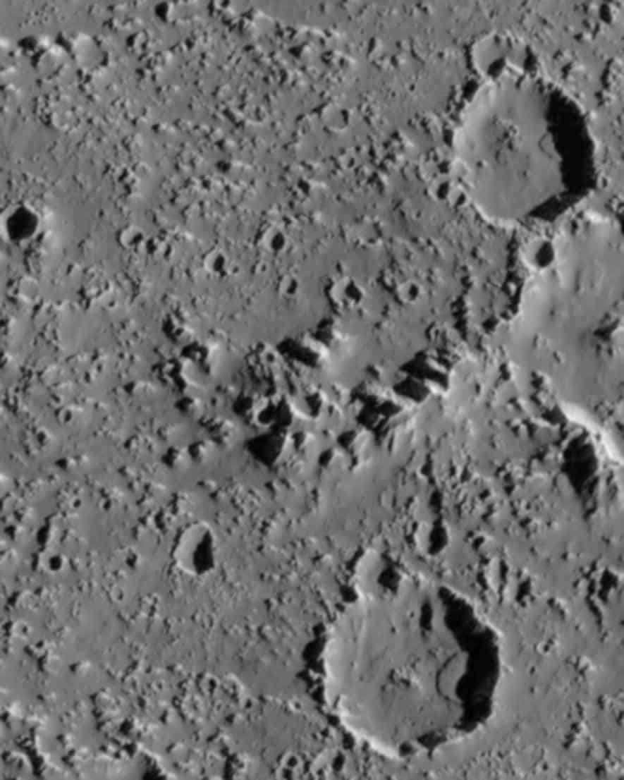 The surface of Callisto shows large landslides within two large impact craters (3-3.5 km wide). The image was taken by the Galileo spacecraft. 